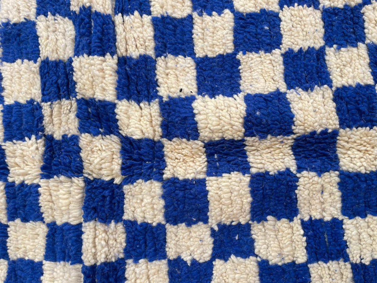 Detail close-up of the textured weave of a checkered blue rug.