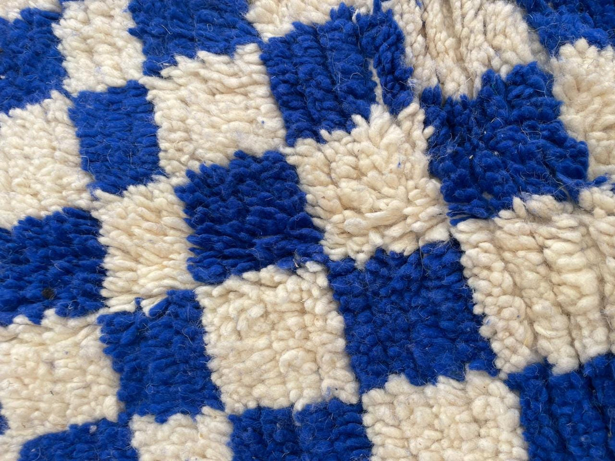 Detail shot of a checkered rug with a focus on its blue and beige colors.