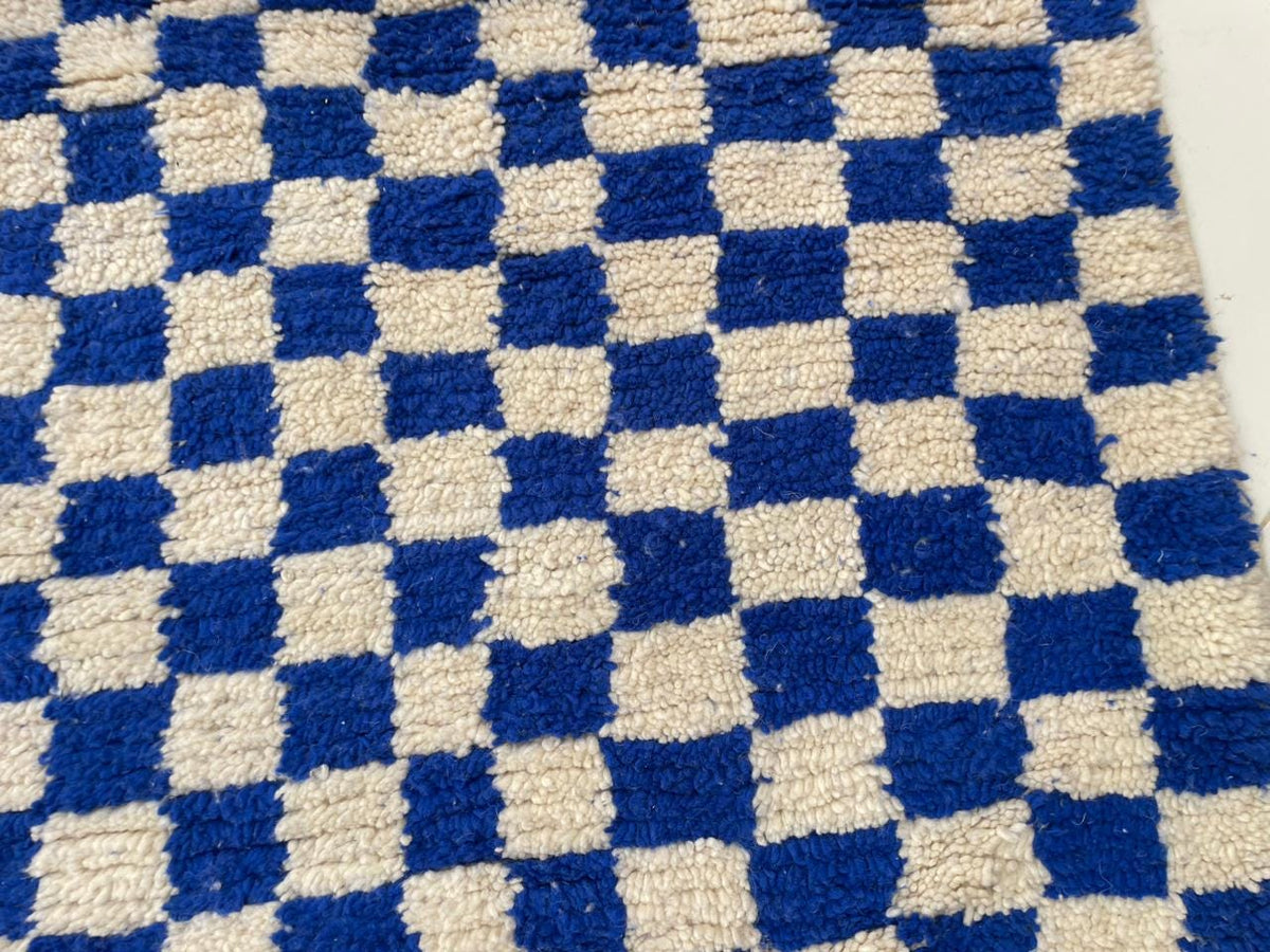 Detail view of a checkered rug showcasing its blue and beige pattern.