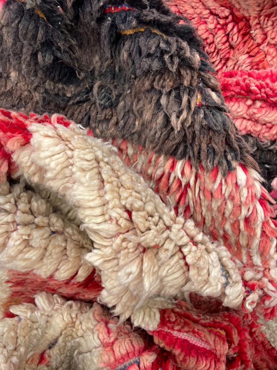 Close-up of a textured surface on a faded red tribal rug with intricate designs.