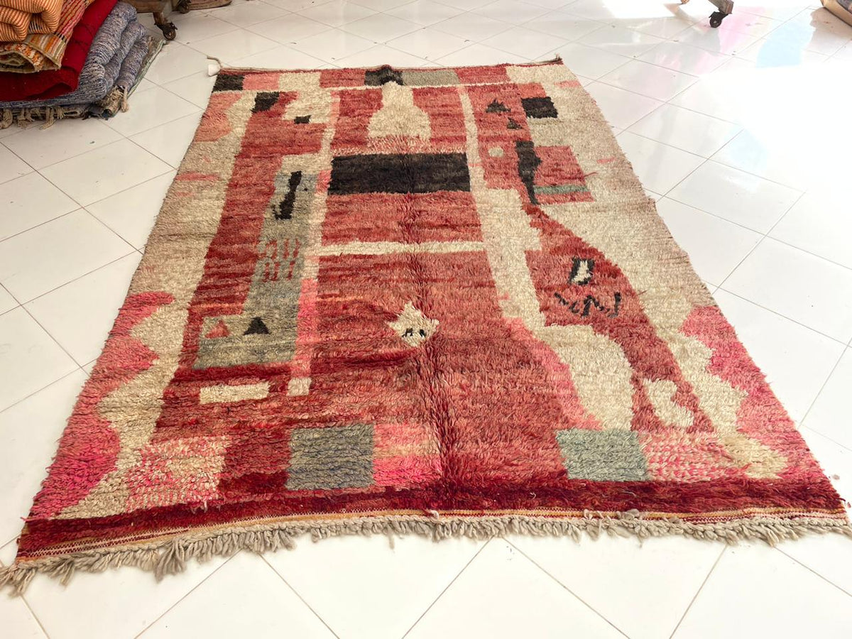 Close-up detail of a faded red Boujaad rug featuring tribal patterns and fringed edges.