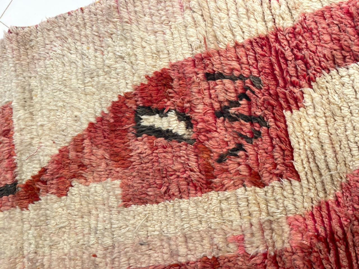 Close-up of a textured surface on a faded red tribal Boujaad rug.