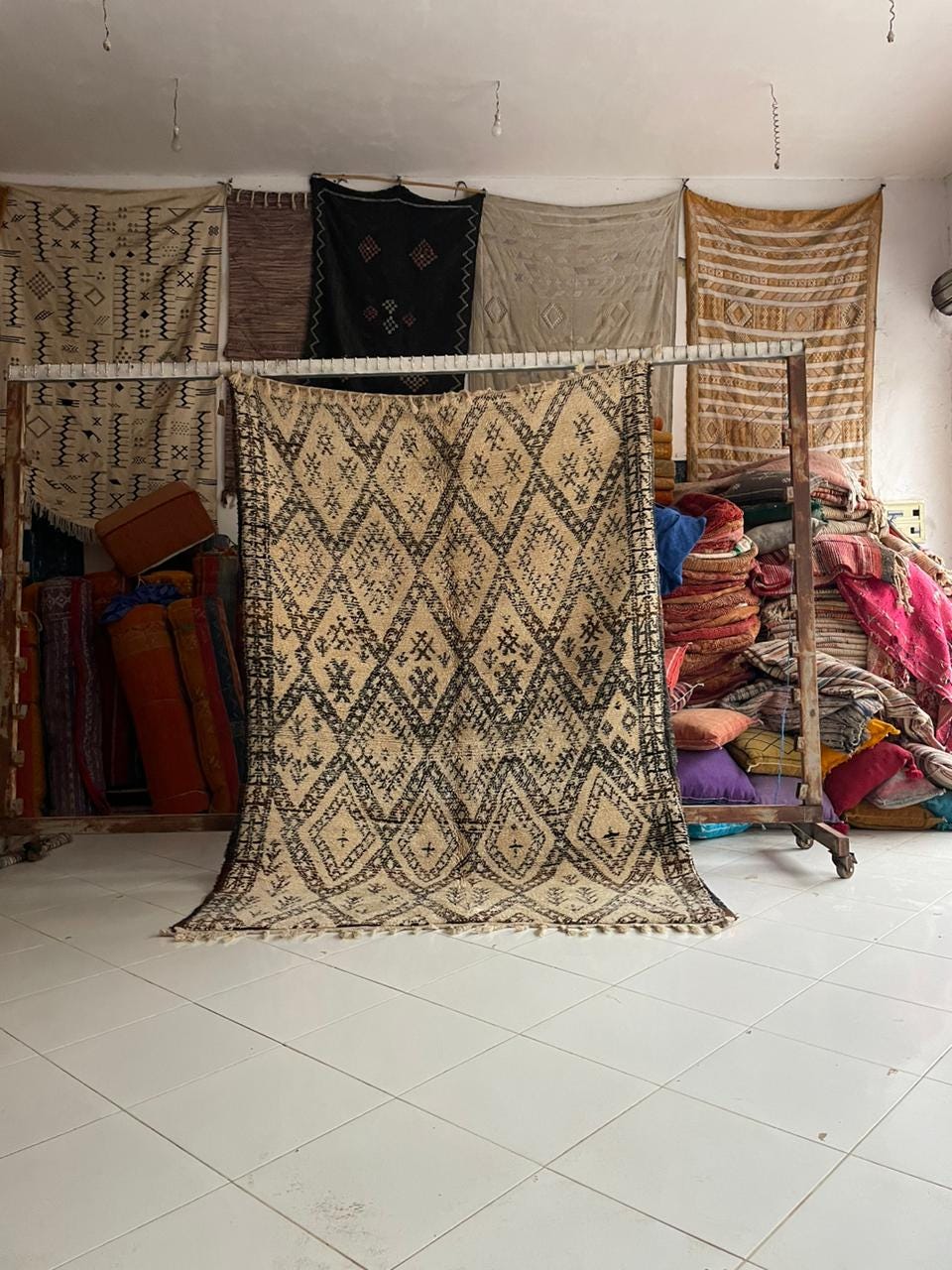Lifestyle shot of a beige and black Moroccan rug with geometric patterns and fringe edges.