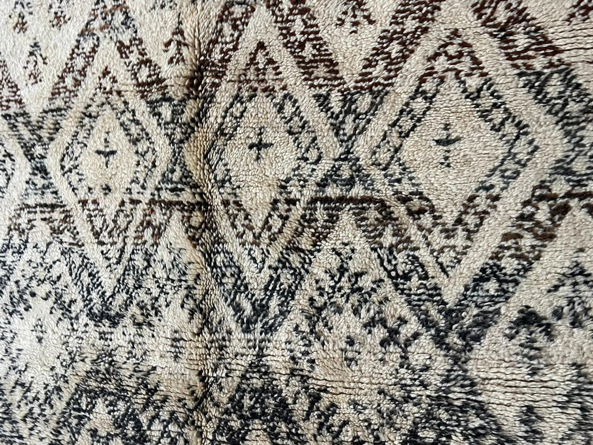 Detail close-up of a vintage Moroccan rug showcasing geometric patterns and a textured surface.