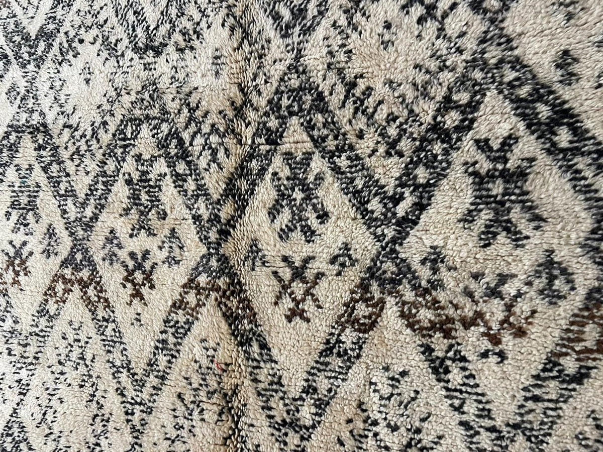 Detail close-up of a vintage Moroccan rug displaying geometric patterns and a textured surface.