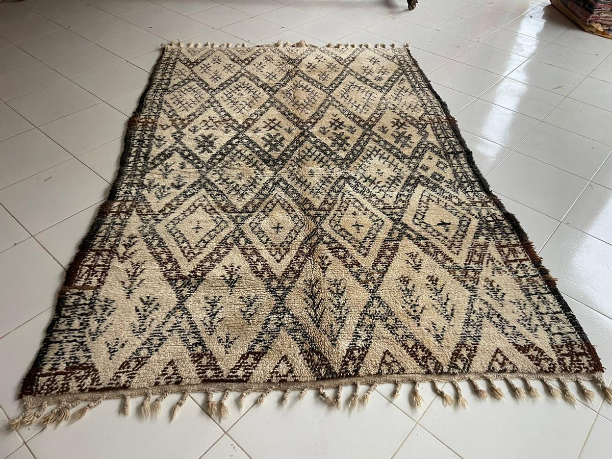 Front view of a beige and black Moroccan rug featuring diamond patterns and fringe edges.
