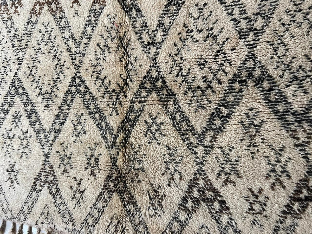 Detail close-up of a vintage Moroccan rug featuring intricate diamond patterns.