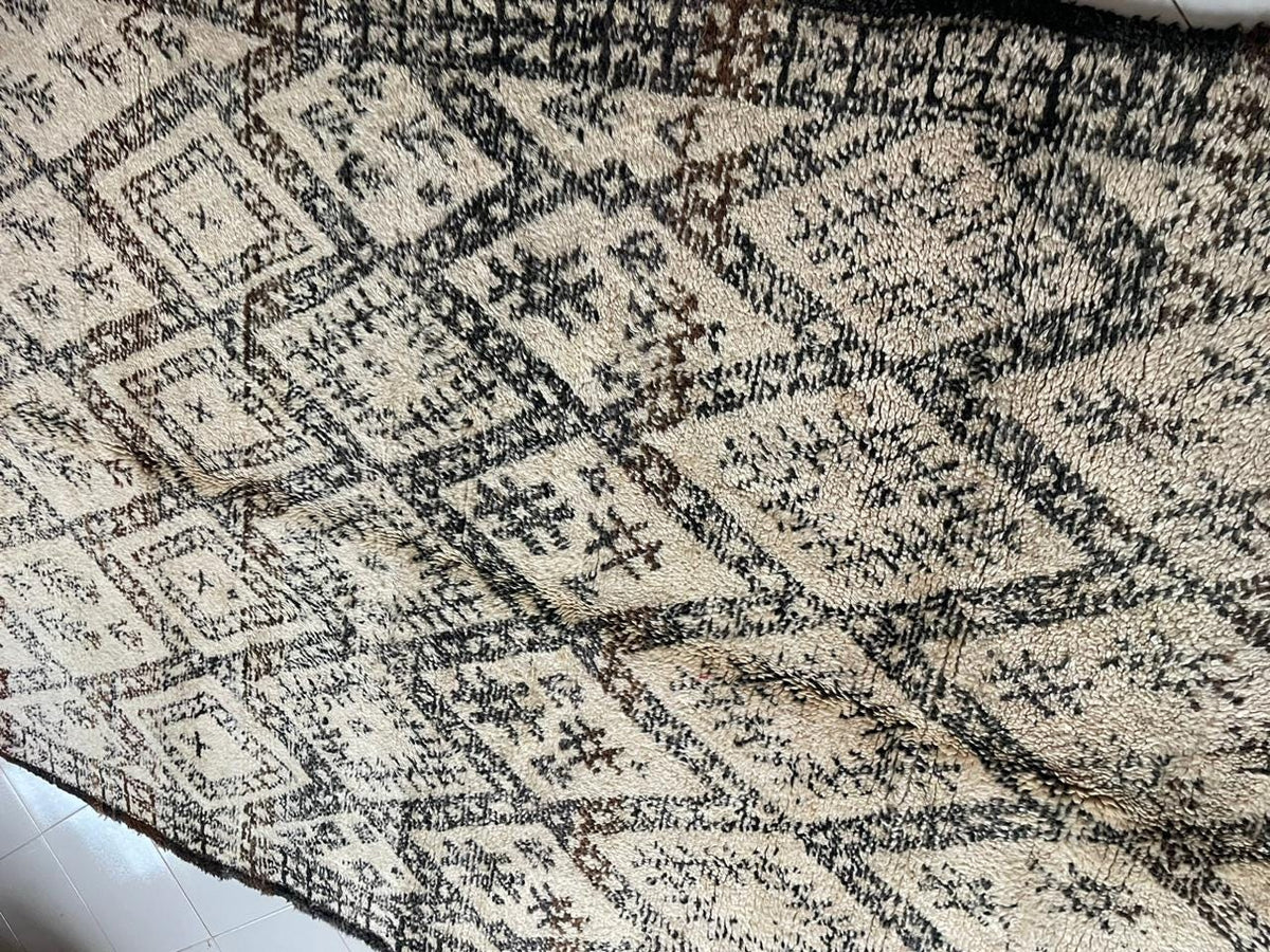 Detail close-up of a vintage Moroccan rug featuring geometric patterns and a textured surface.