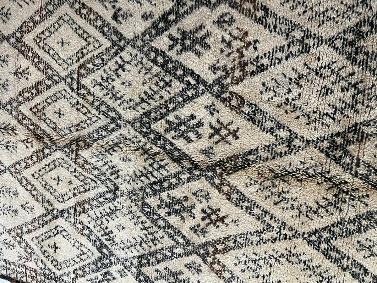 Detail close-up of a vintage Moroccan rug with geometric patterns and a textured surface.