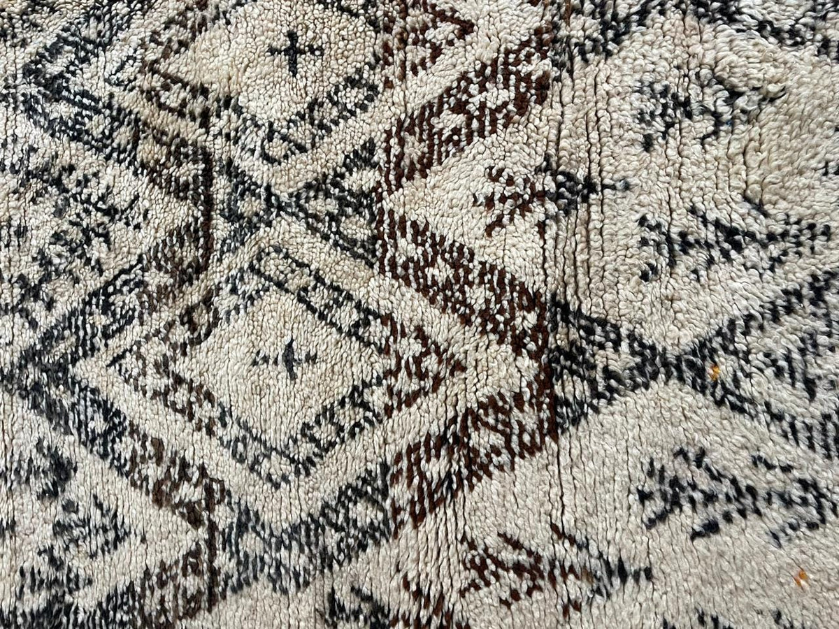 Detail close-up of a vintage Moroccan rug with floral motifs and a textured surface.