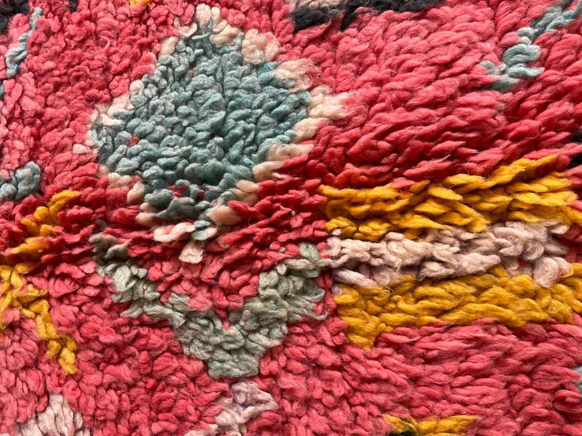 Detail shot of a pink Moroccan rug highlighting its geometric patterns and textured surface.