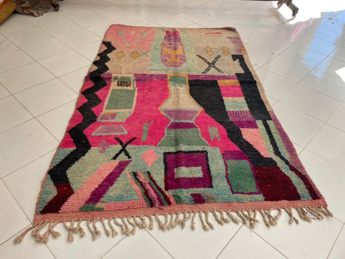 Front view of a pink vintage Moroccan rug featuring geometric patterns on a solid background.