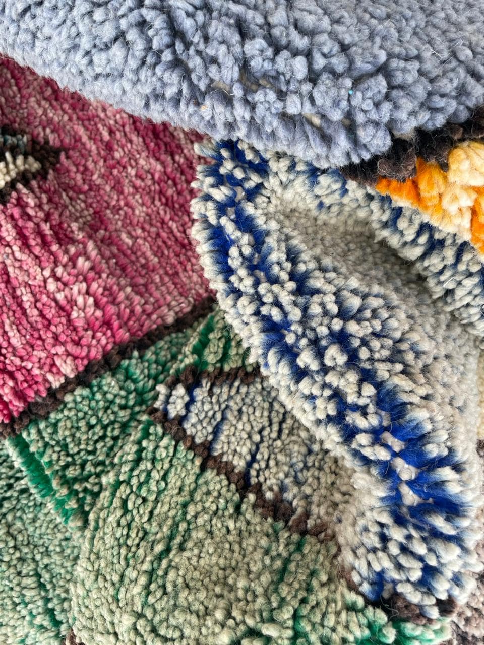 Various rugs displayed with textured patterns and colorful designs in red, blue, and green.