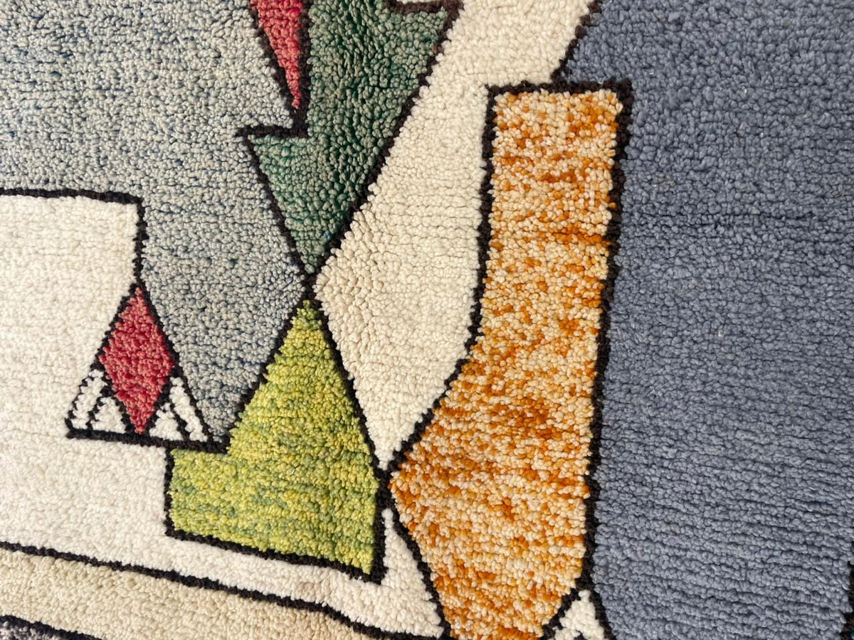 Detail shot of a tribal area rug featuring geometric patterns in orange, green, and red.