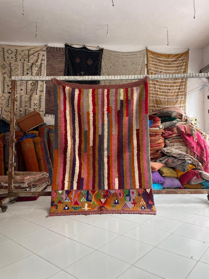 Lifestyle shot of a vintage Moroccan rug featuring tribal patterns in red, orange, and purple.