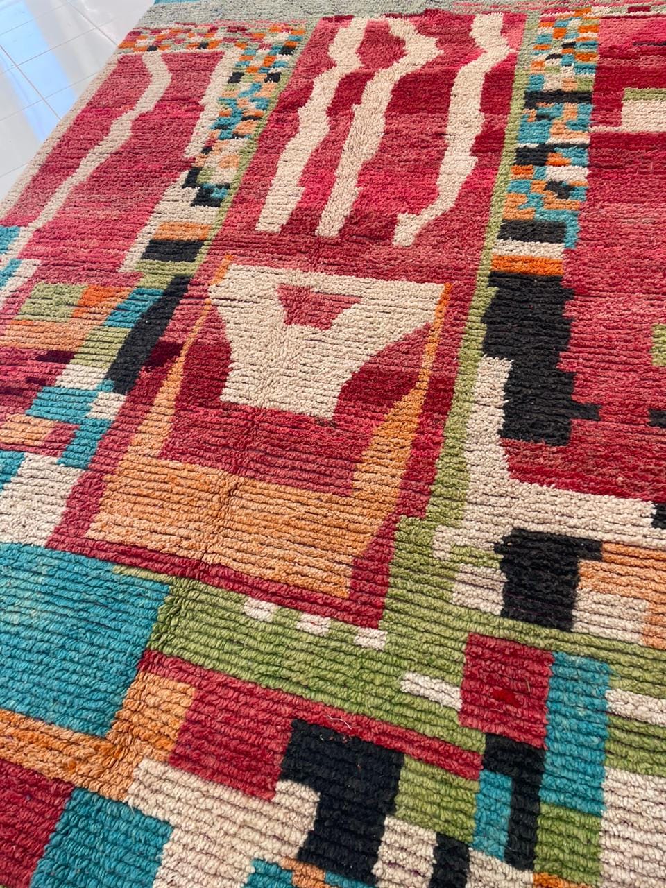 Close-up detail of a vintage Moroccan rug with intricate tribal patterns and fringed edges.