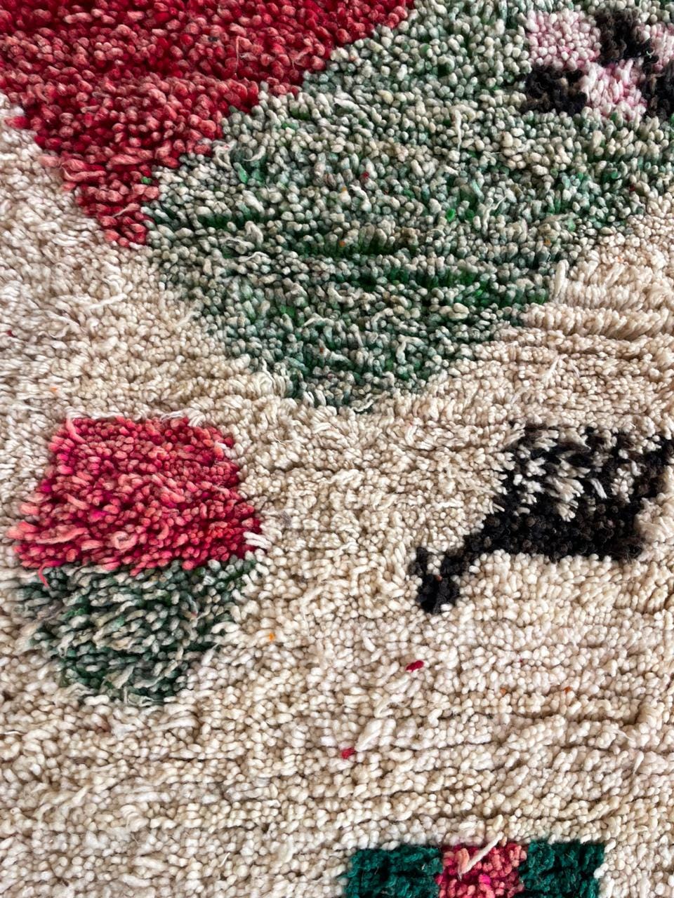 Close-up detail of the vintage rug's textured fabric with geometric patterns in red and green.