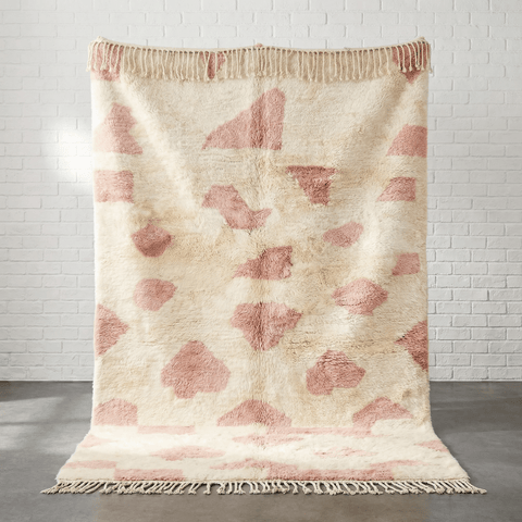 Lifestyle shot of a baby pink Moroccan rug in a natural setting with beige tones.