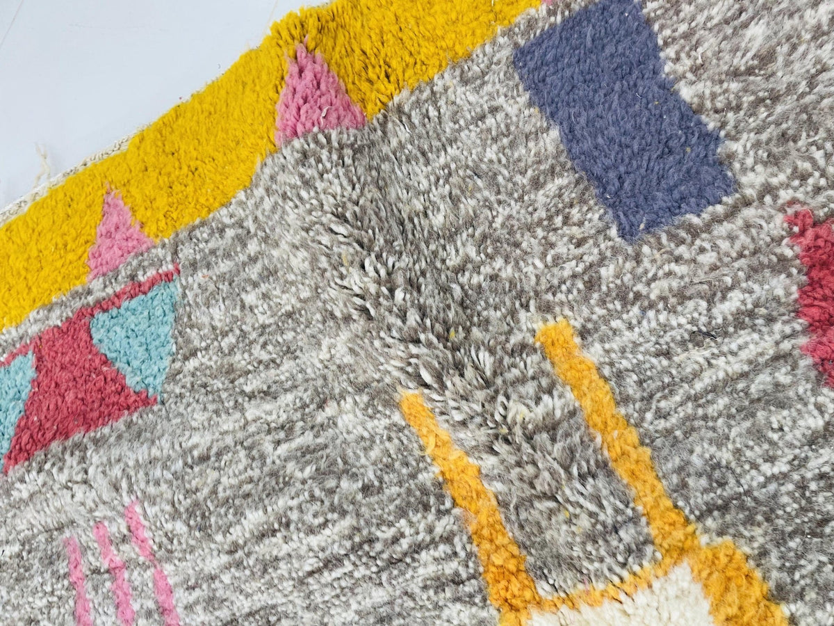 Detail view of the red vintage Moroccan rug displaying geometric shapes in gray, yellow, and pink.