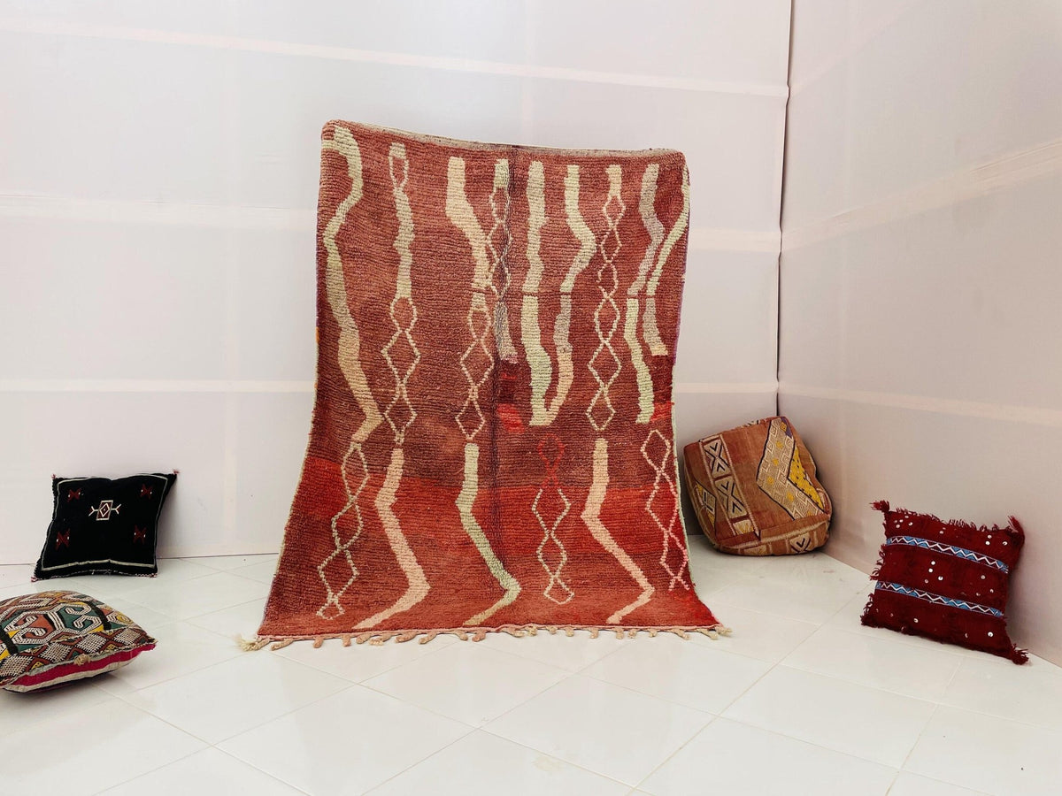 Lifestyle shot of a vintage Moroccan rug featuring tribal patterns in red and white.