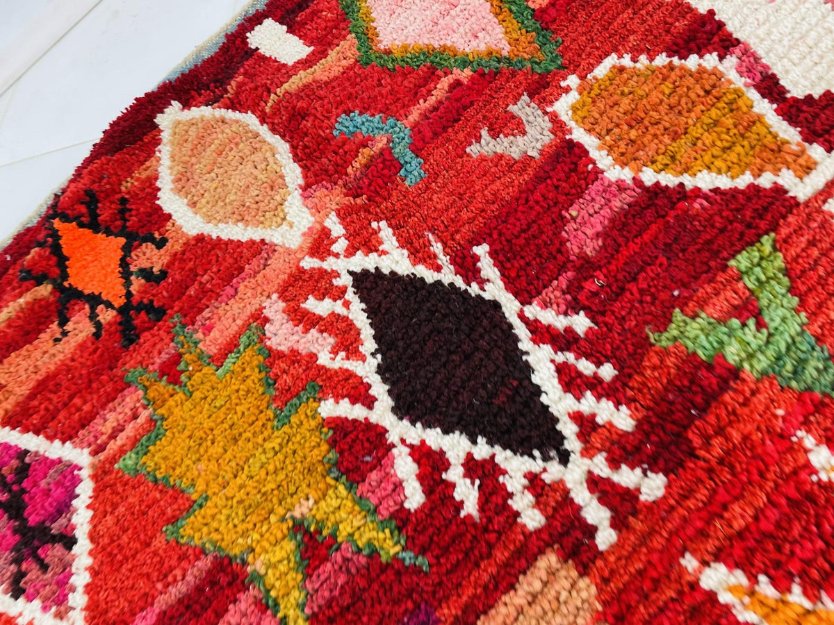 Detail shot of a red vintage Moroccan rug featuring tribal patterns and colorful accents.