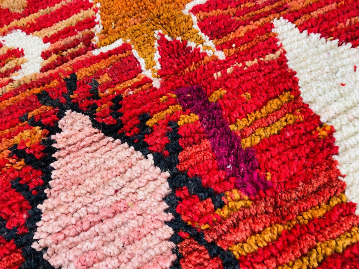 Close-up of the vibrant tribal designs and textures on a red vintage Moroccan rug.