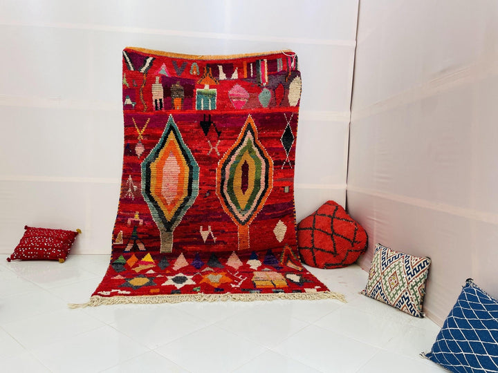 Lifestyle view of a red vintage Boujaad Moroccan rug with tribal patterns on a white background.