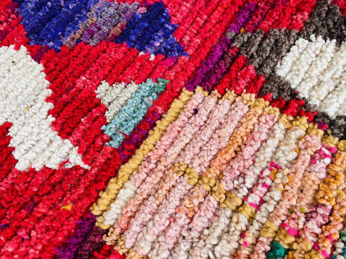 Detail shot of a vintage Boujaad Moroccan rug in red and pink with tribal patterns and texture.