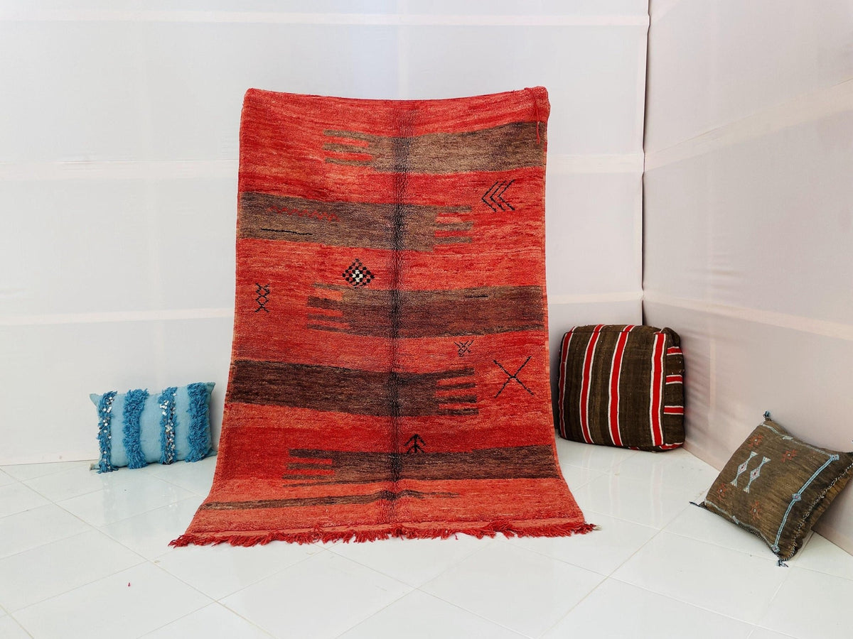 Lifestyle shot of a red vintage Boujaad Moroccan rug with tribal patterns in a studio setting.