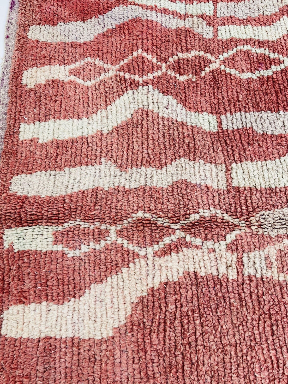 Detail shot of a vintage Moroccan rug featuring geometric patterns and a soft texture.