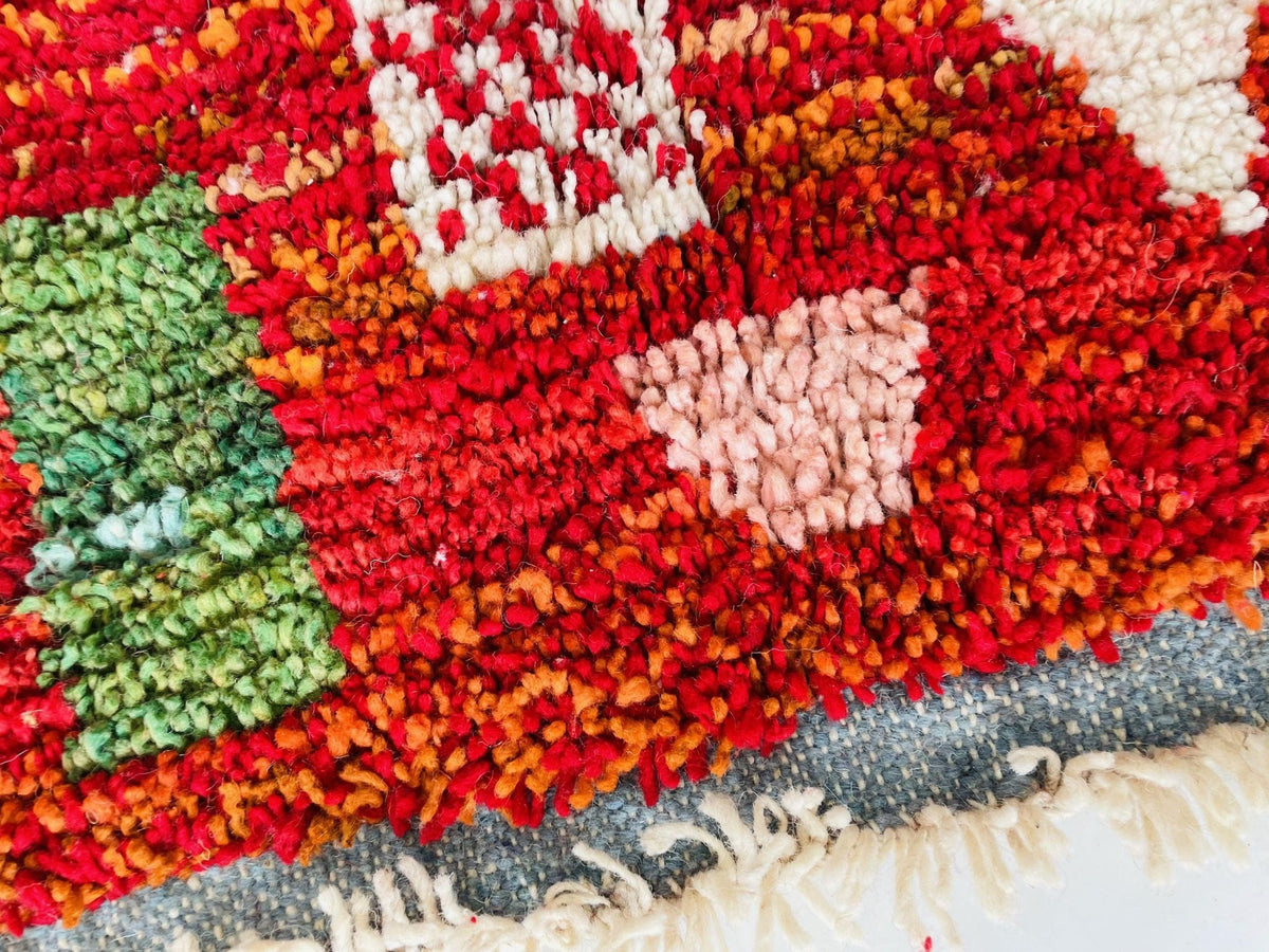 Detail close-up of the textured fibers and colorful patterns on a red vintage Moroccan rug.