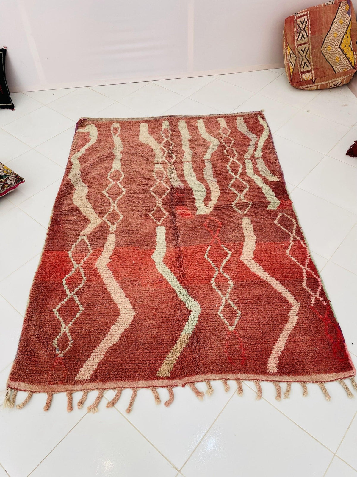 Front view of a vintage Moroccan rug with tribal patterns and fringed edges in red and white.