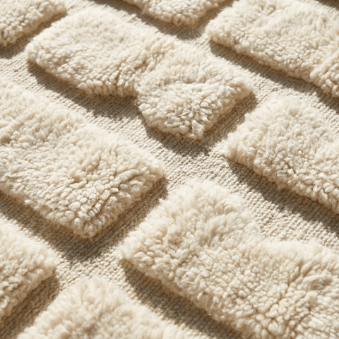 Close-up detail of a beige Moroccan rug showcasing a textured surface and soft fibers.