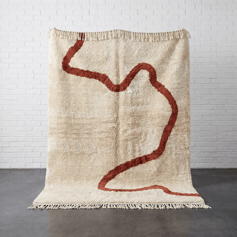 Front view of a beige Moroccan rug featuring an abstract pattern with red accents.