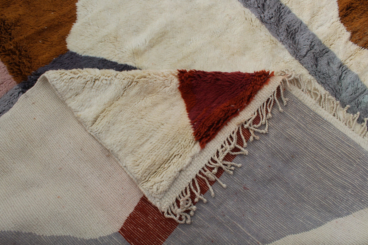 Detail close-up of a Moroccan rug showcasing geometric patterns in beige, red, and gray tones.