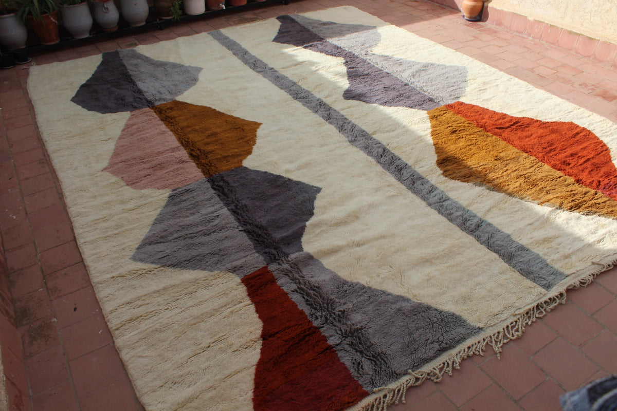 Lifestyle view of a Moroccan extra-large rug featuring geometric patterns and fringe edges in warm colors.