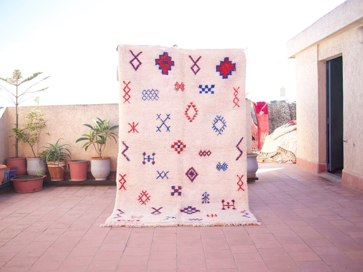 Lifestyle shot of a multicolor Beni Ourain rug with geometric patterns on a natural background.