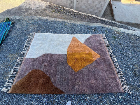 Top view of a brown and orange geometric Moroccan rug with fringed edges.