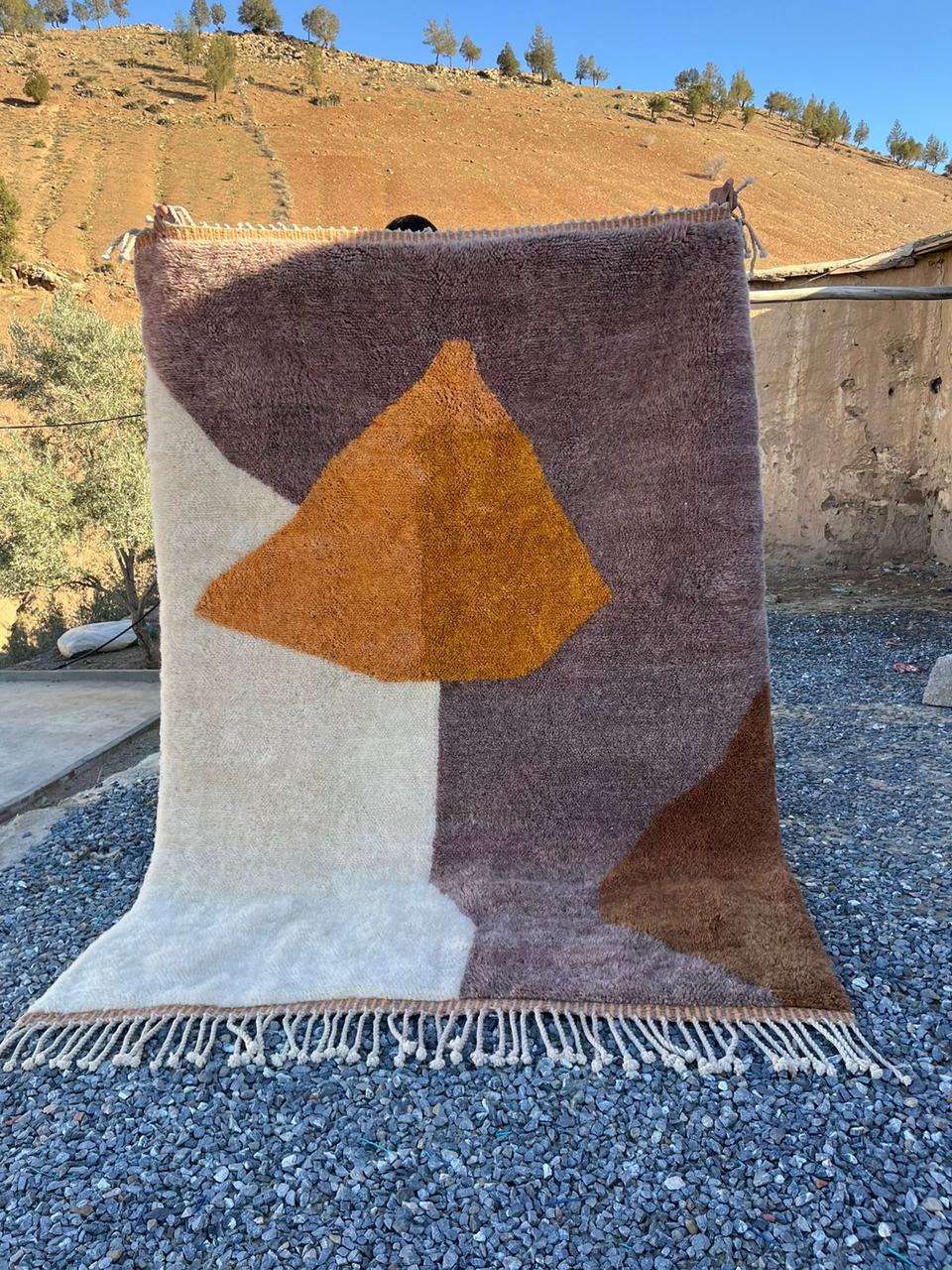 Lifestyle shot of a brown and orange geometric Moroccan rug with a soft texture.
