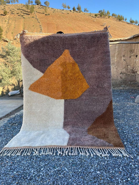Lifestyle shot of a brown and orange geometric Moroccan rug with a soft texture.