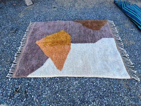 Top view of a brown and orange geometric Moroccan rug featuring fringed edges.