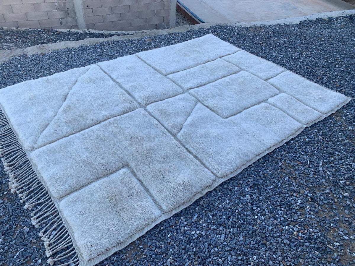 Detail view of a Moroccan rug showcasing a geometric design in soft white and beige tones.