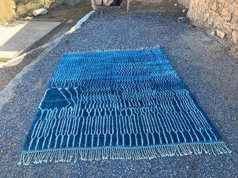 Front view of a blue Moroccan rug with a geometric design and fringed edges.