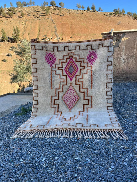 Lifestyle view of a cream and pink Moroccan rug showcasing geometric designs and fringe detailing.