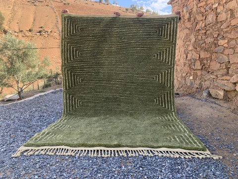 Front view of the olive green Moroccan rug highlighting its large size and fringed edges.