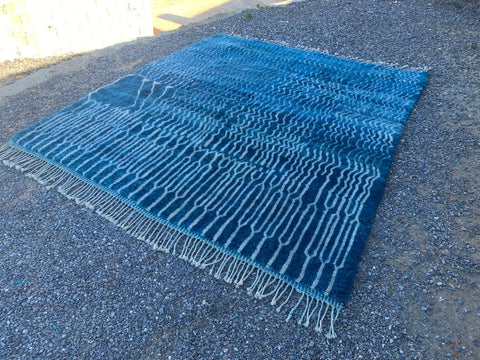 Lifestyle view of a large blue Moroccan rug featuring fringed edges.