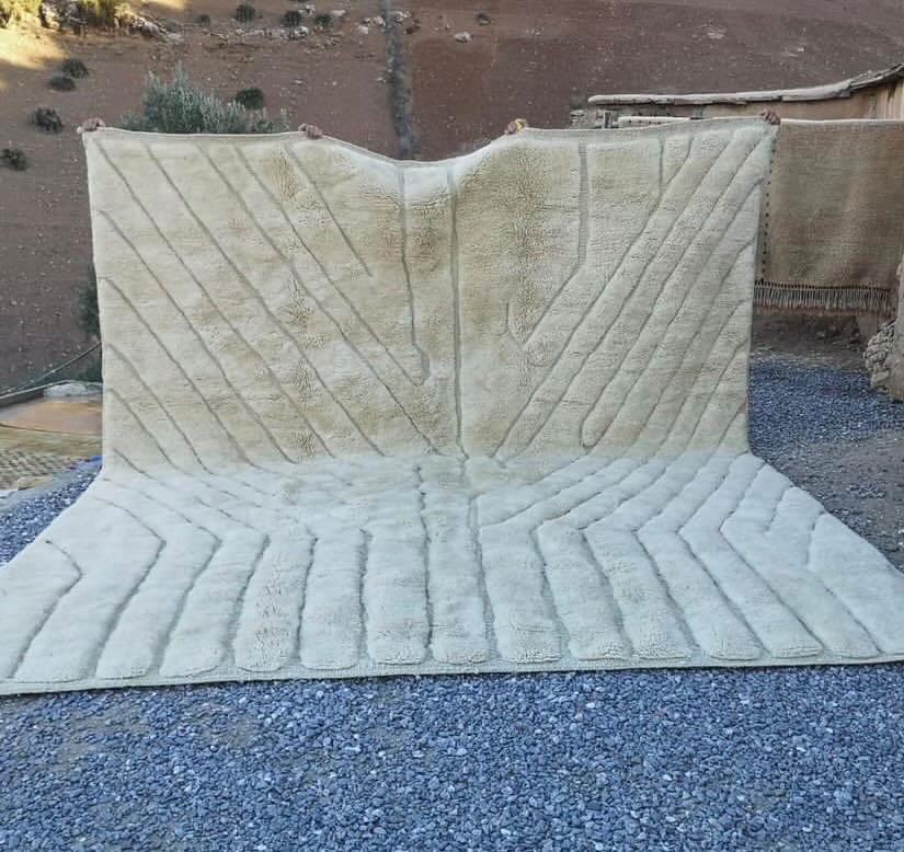 Front view of a large beige Moroccan rug with a textured pattern on a natural background.