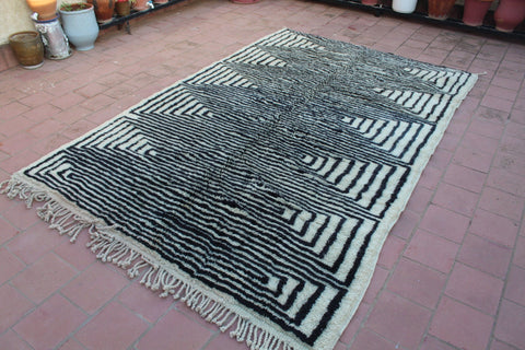 Lifestyle view of a black and white rug featuring geometric patterns and fringe edges.