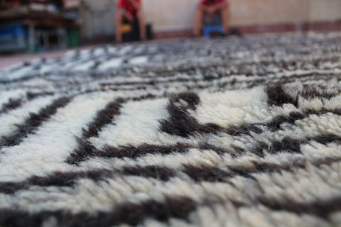 Detail view of a black and white rug with thick pile and abstract design.