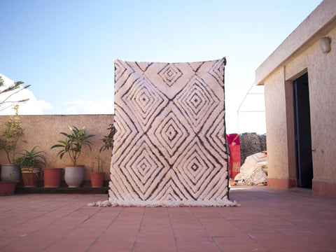 Lifestyle shot of a black and white rug featuring geometric patterns and fringe edges.